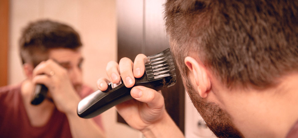 homem cortando o próprio cabelo com maquina em casa